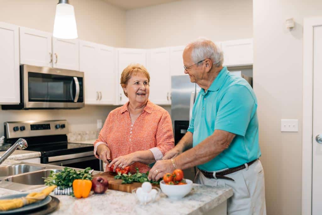 couple smiling and making a salad