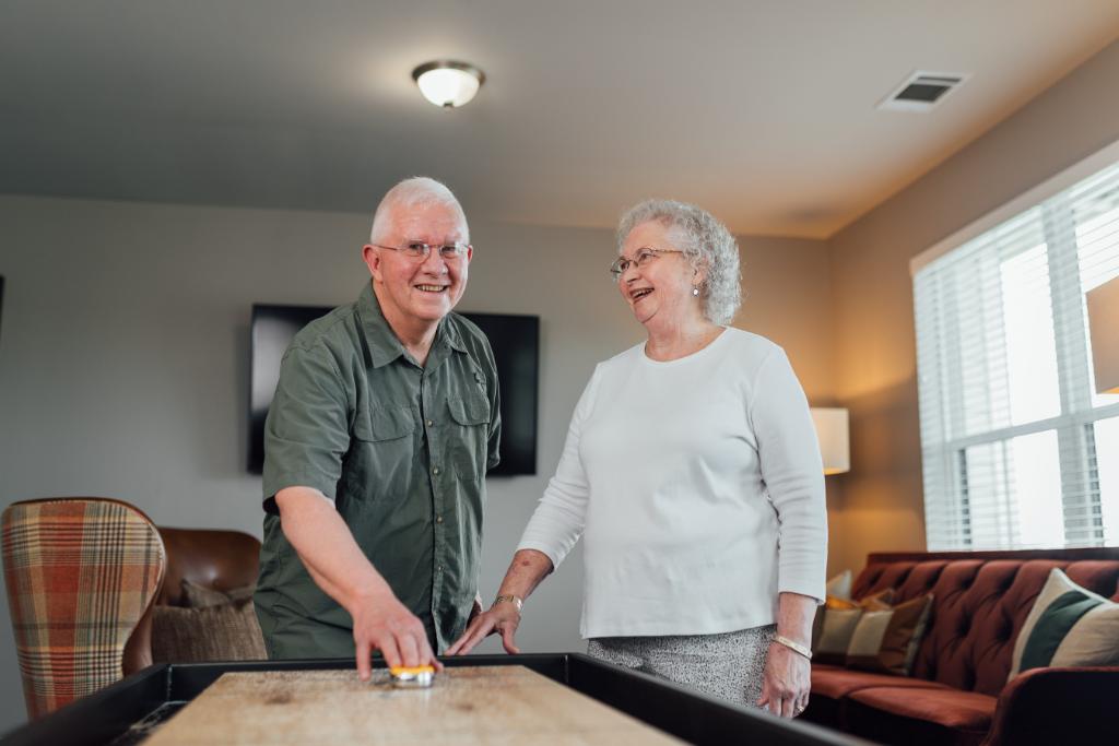 Smiling resident couple playing shuffleboard