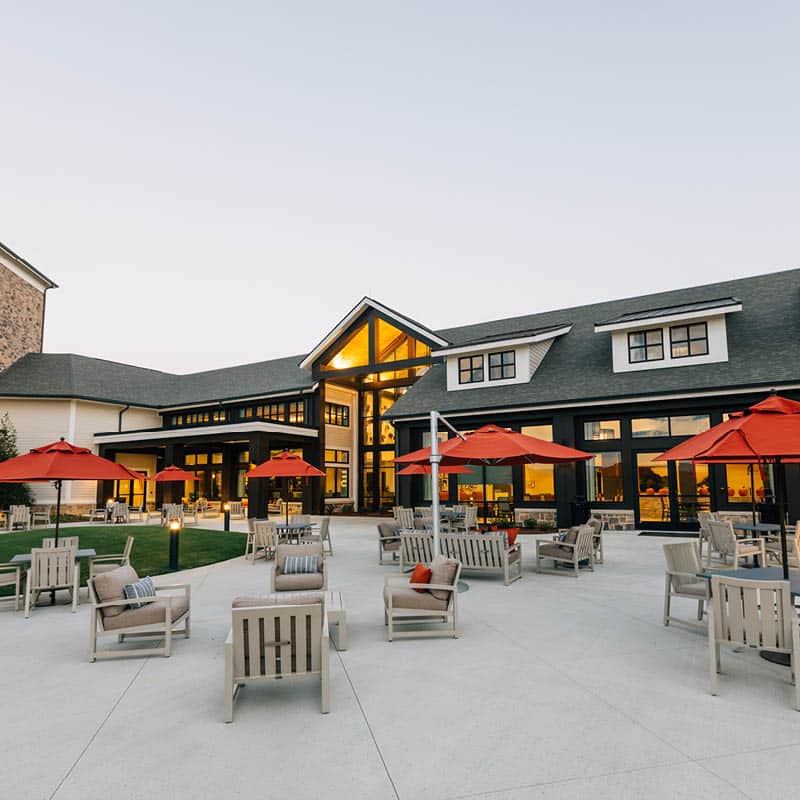 outdoor courtyard at The Spires with sets of chairs, tables and orange umbrellas