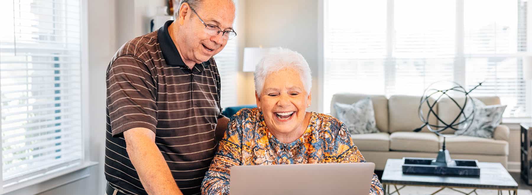 Smiling couple looking at a laptop computer in their apartment